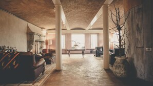 A spacious living area with a stone floor, a leather sofa, a coffee table, and a potted plant. - La Luna nel Pozzo (Parma)