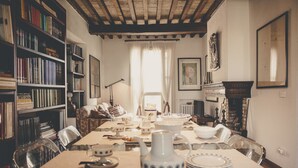 A dining area with a long table set for a meal, surrounded by bookshelves and a fireplace. - La Luna nel Pozzo (Parma)