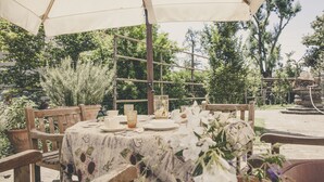 An outdoor dining area with a round table set for four, surrounded by wooden chairs. - La Luna nel Pozzo (Parma)