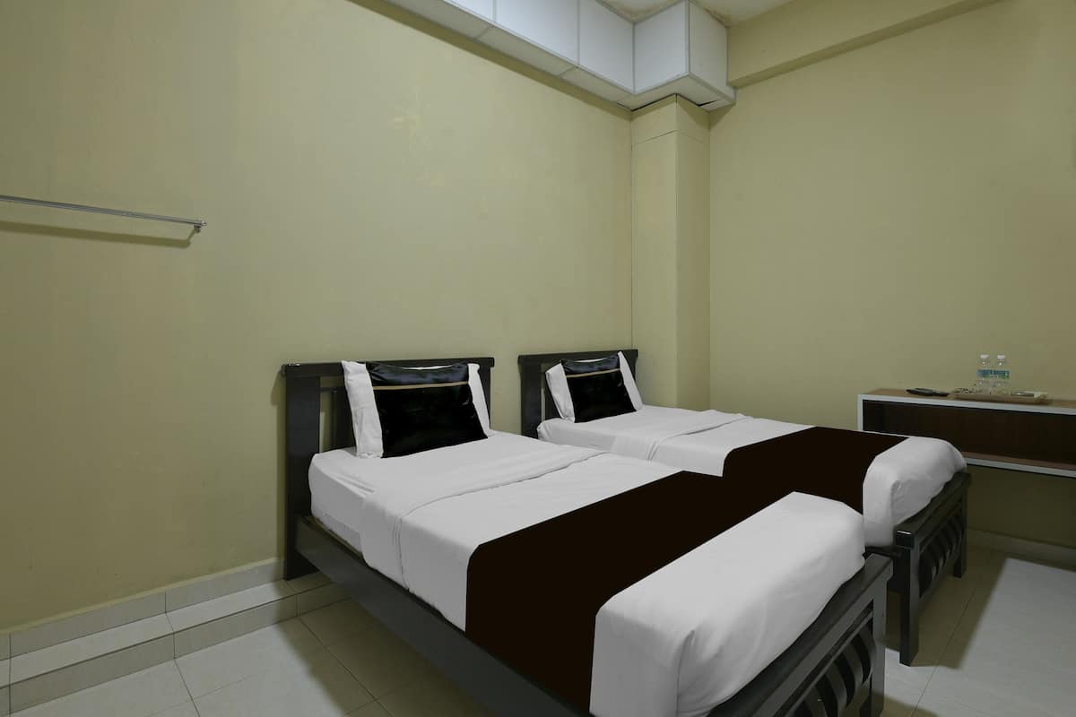 A room with two beds, a small desk, and a shelf with items.