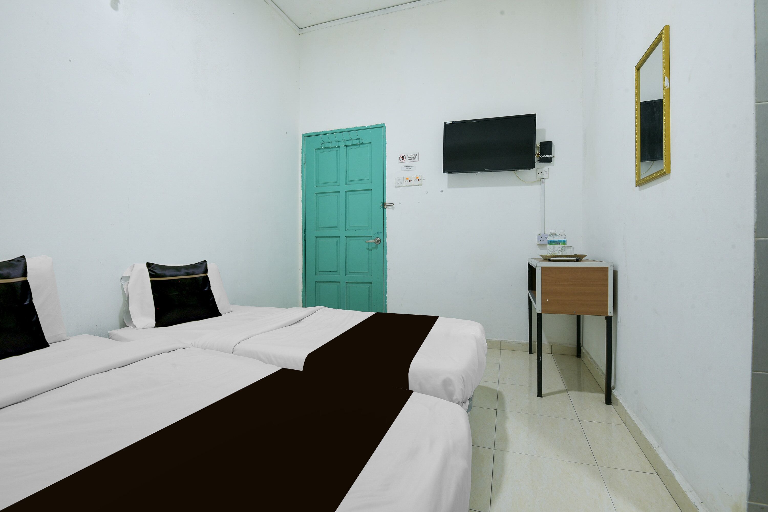A hotel room with a bed, a desk, a television, and a door.