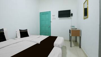 A hotel room with a bed, a desk, a television, and a door.