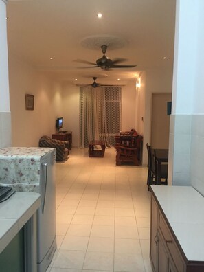 A spacious living area with a ceiling fan, a television, and a dining table with chairs. - Medic Tony Vacation Home (Ipoh)