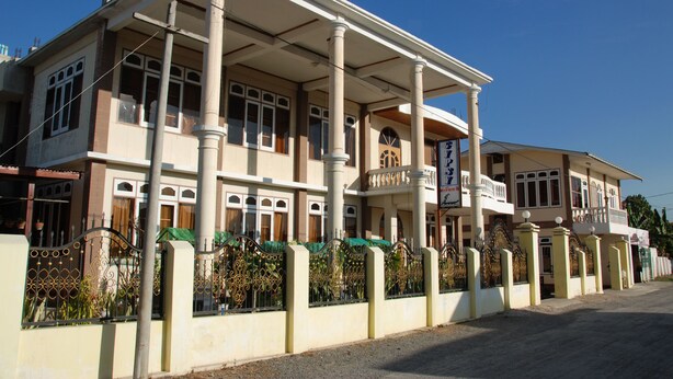 A two-story building with a balcony, columns, and a gated entrance. - Gypsy Inn (Nyaungshwe)
