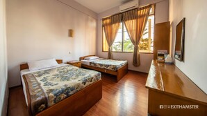 A hotel room with two wooden beds, a wooden desk, a mirror, and a window with curtains. - Gypsy Inn (Nyaungshwe)