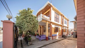 A two-story building with a balcony, potted plants, and outdoor seating. - Gypsy Inn (Nyaungshwe)