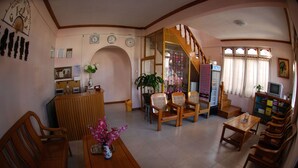 A cozy living room with wooden furniture, a TV, and a staircase leading to another level. - Gypsy Inn (Nyaungshwe)