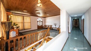 A spacious hallway with wooden flooring, a staircase with a wooden railing, and a seating area with chairs and a table. - Gypsy Inn (Nyaungshwe)