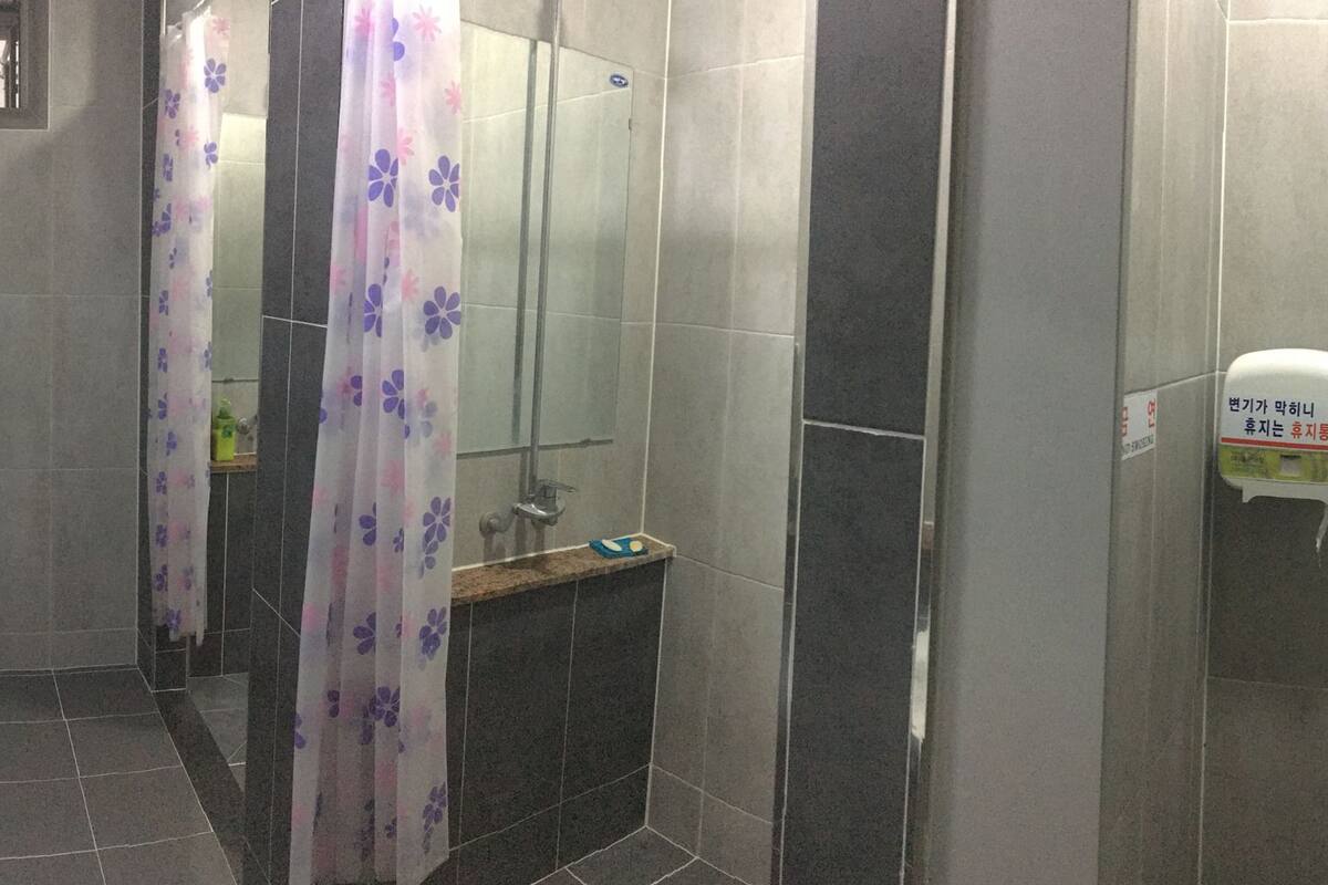 Des toilettes pour hommes comprenant des urinoirs, un lavabo, un sèche-mains et un distributeur de savon.