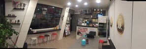 A café with a counter, stools, a coffee machine, and a menu board. - JJBro Hostel Guest House (Mokpo)
