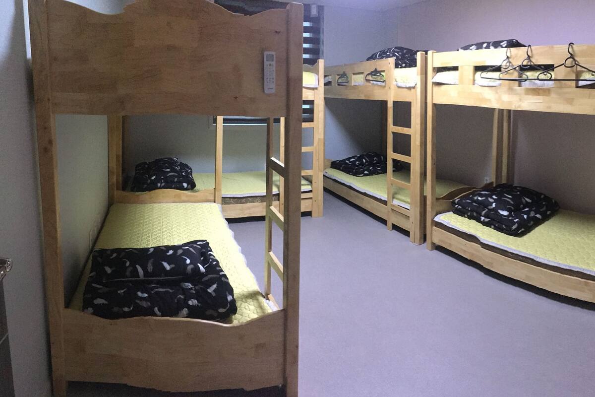 Une chambre de dortoir avec des lits superposés, chacun étant équipé d’un oreiller et d’une couverture.