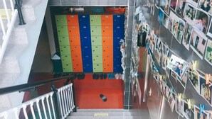 A multi-level indoor space with lockers, a staircase, and a wall with photos. - JJBro Hostel Guest House (Mokpo)