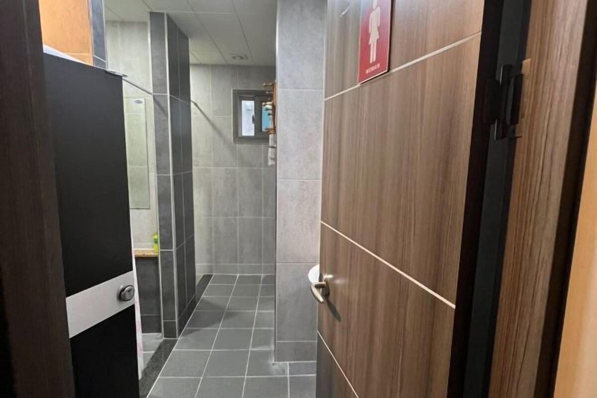 Un couloir étroit aux murs carrelés, avec une porte en bois sur la droite.