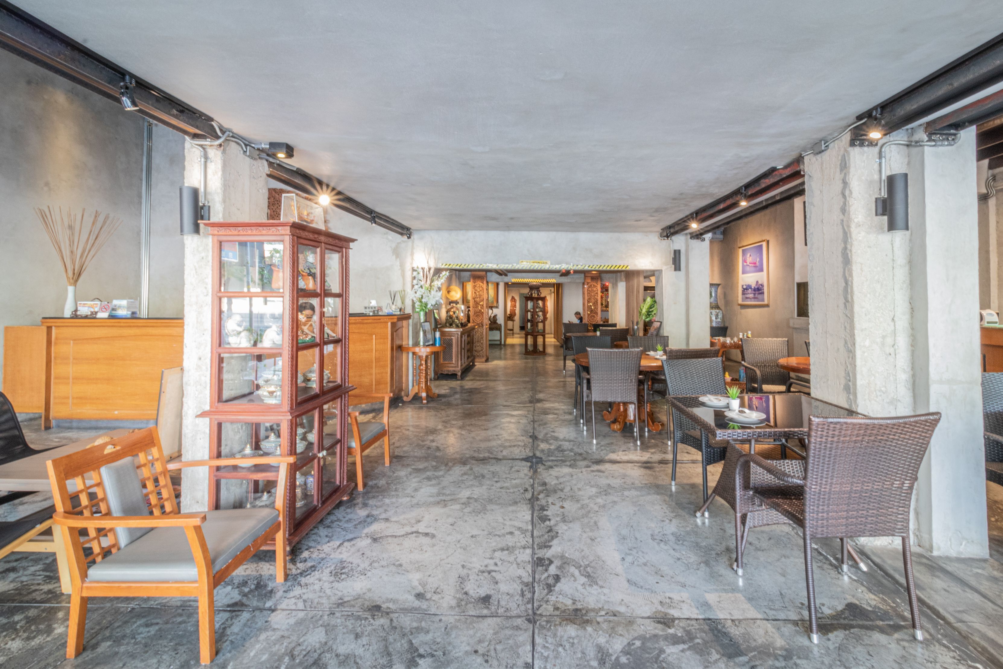 A spacious lobby with a high ceiling, featuring a central open area with seating arrangements and a wooden cabinet with glass doors.