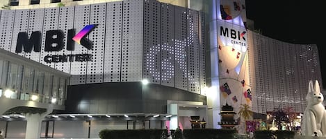 A modern MBK Center building with a prominent MBK logo, large windows, and a decorative light display.