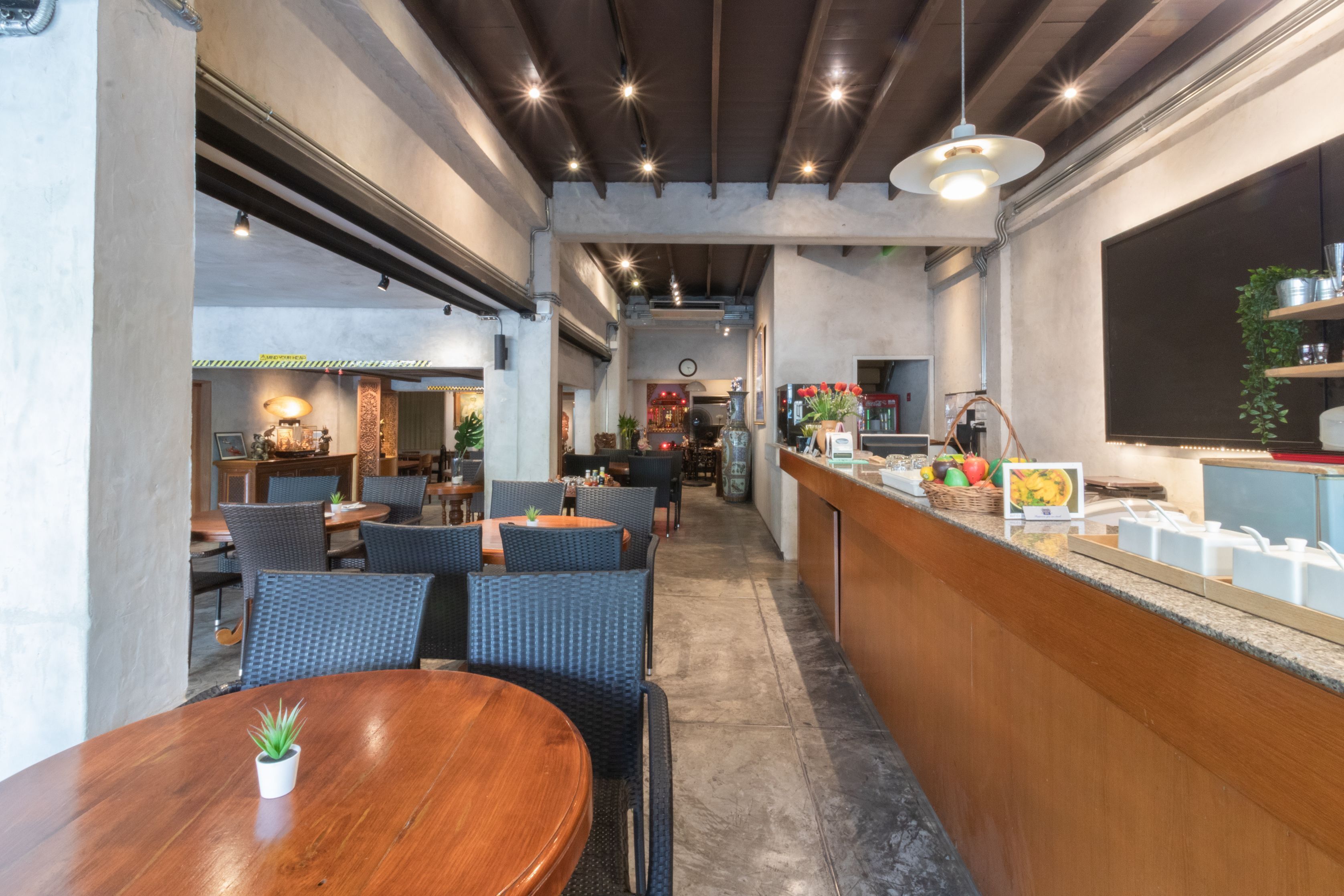 Ein Restaurant mit einem Essbereich aus Holz, einer Bar mit einer Theke und einer Küche im Hintergrund.