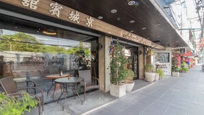 Fachada com um letreiro que diz "In Town Coffee & Restaurant" e área externa com cadeiras e mesas de vime.
