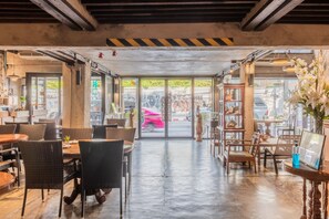 An interior with a central open space, tables, chairs, and a view through a glass door to the outside.
