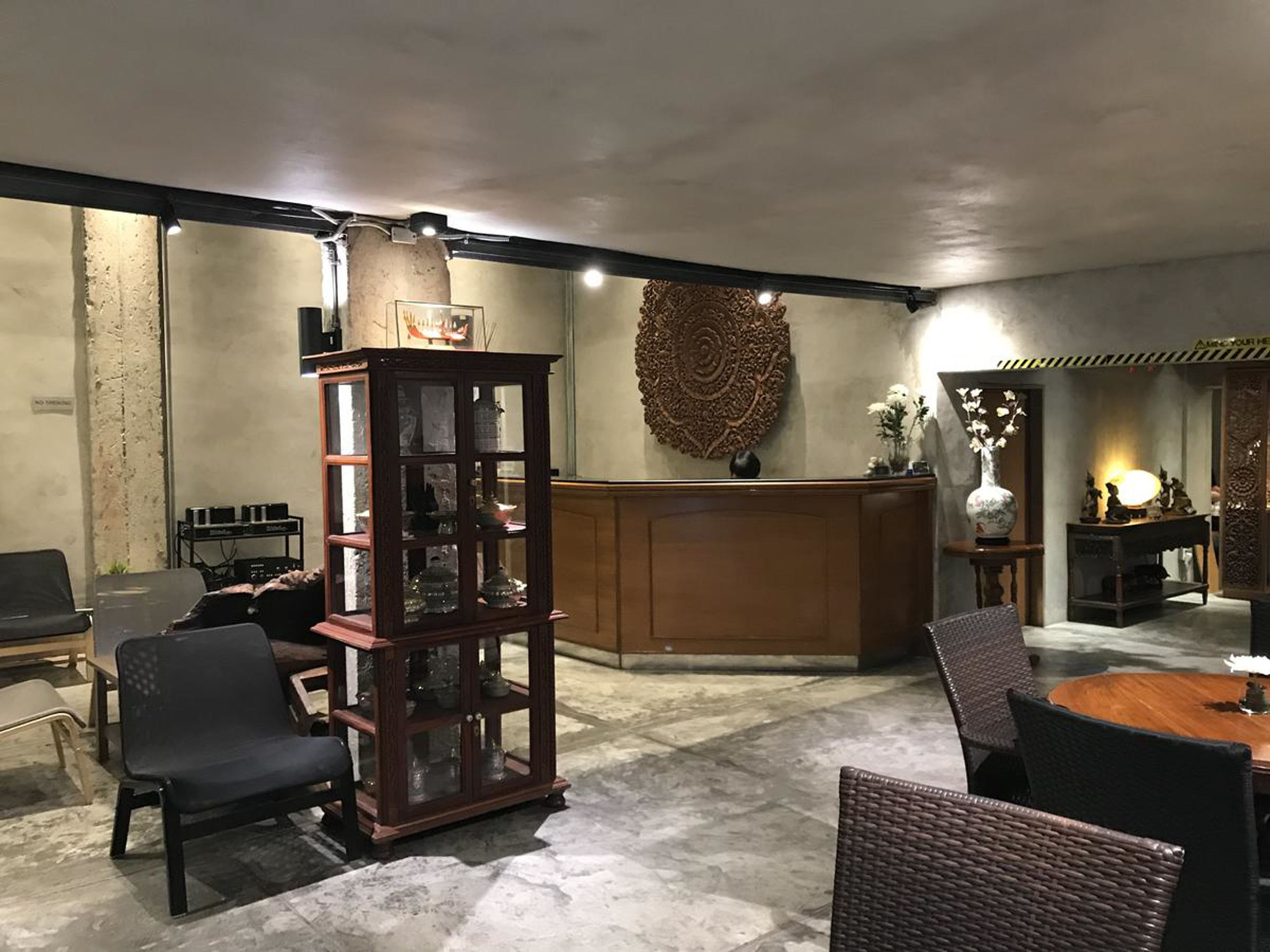 A lobby with a reception desk, a wooden display cabinet, and wicker furniture.