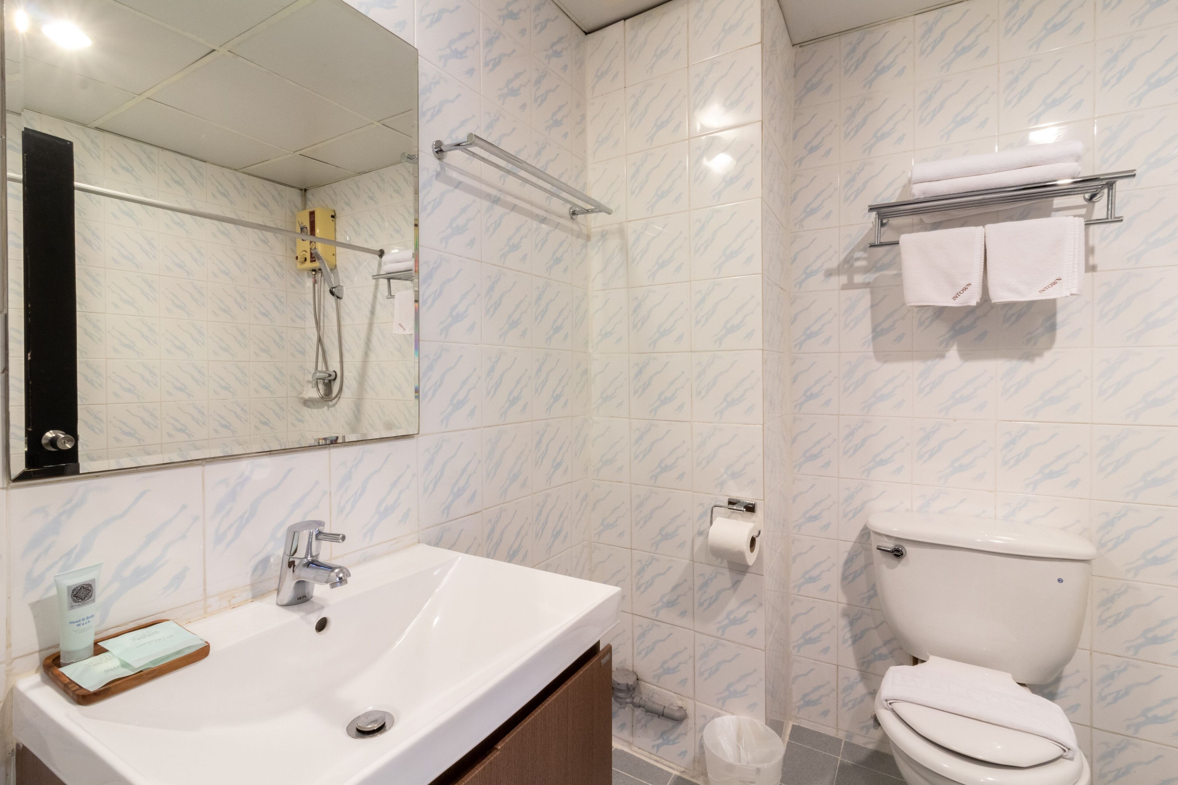Un baño con lavamanos blanco, espejo, inodoro y zona de ducha.