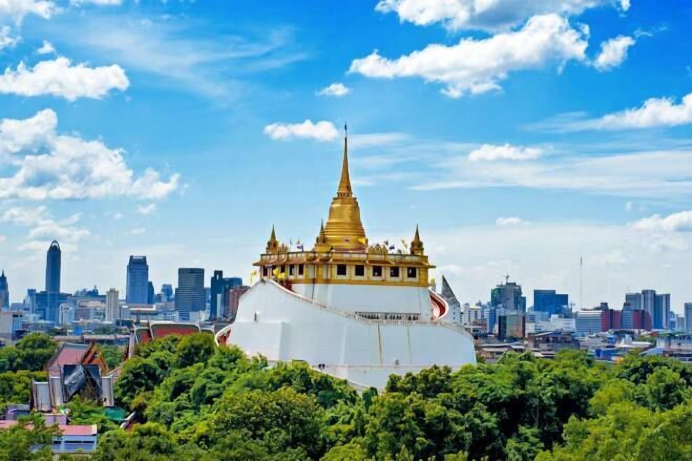 A large white building with a golden spire, surrounded by a cityscape and greenery.