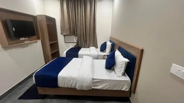 Een hotelkamer met een bed, een aan de muur bevestigde televisie en een raam met gordijnen.