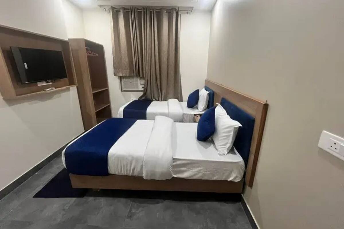 Een hotelkamer met een bed, een aan de muur bevestigde televisie en een raam met gordijnen.