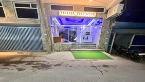 Een hotelingang met een bord waarop 'HOTEL THE RISE' staat.