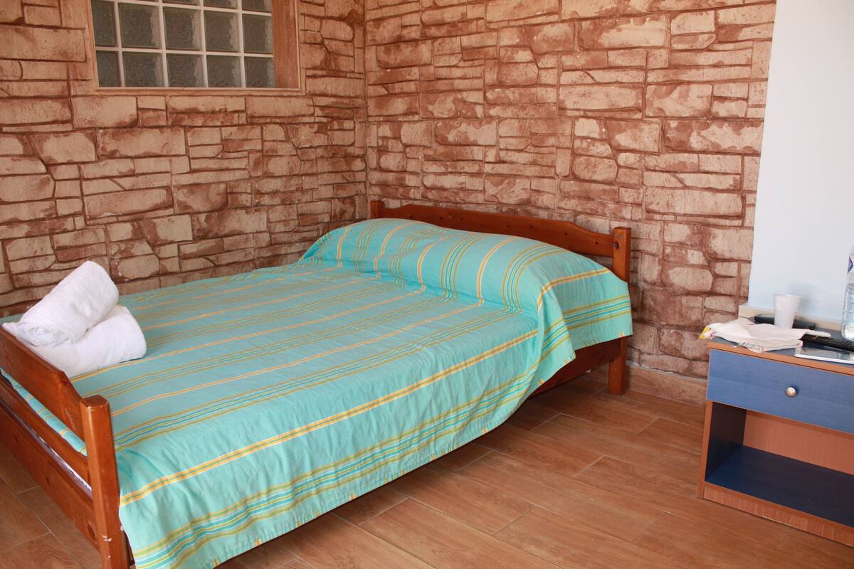 A single bed with a striped bedspread, a wooden headboard, and a nightstand with a lamp.