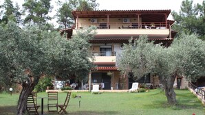 A two-story building with a balcony, surrounded by trees and a grassy lawn. - Villa Bambola (Nea Propontida)