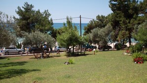 A grassy area with trees and a view of the sea. - Villa Bambola (Nea Propontida)