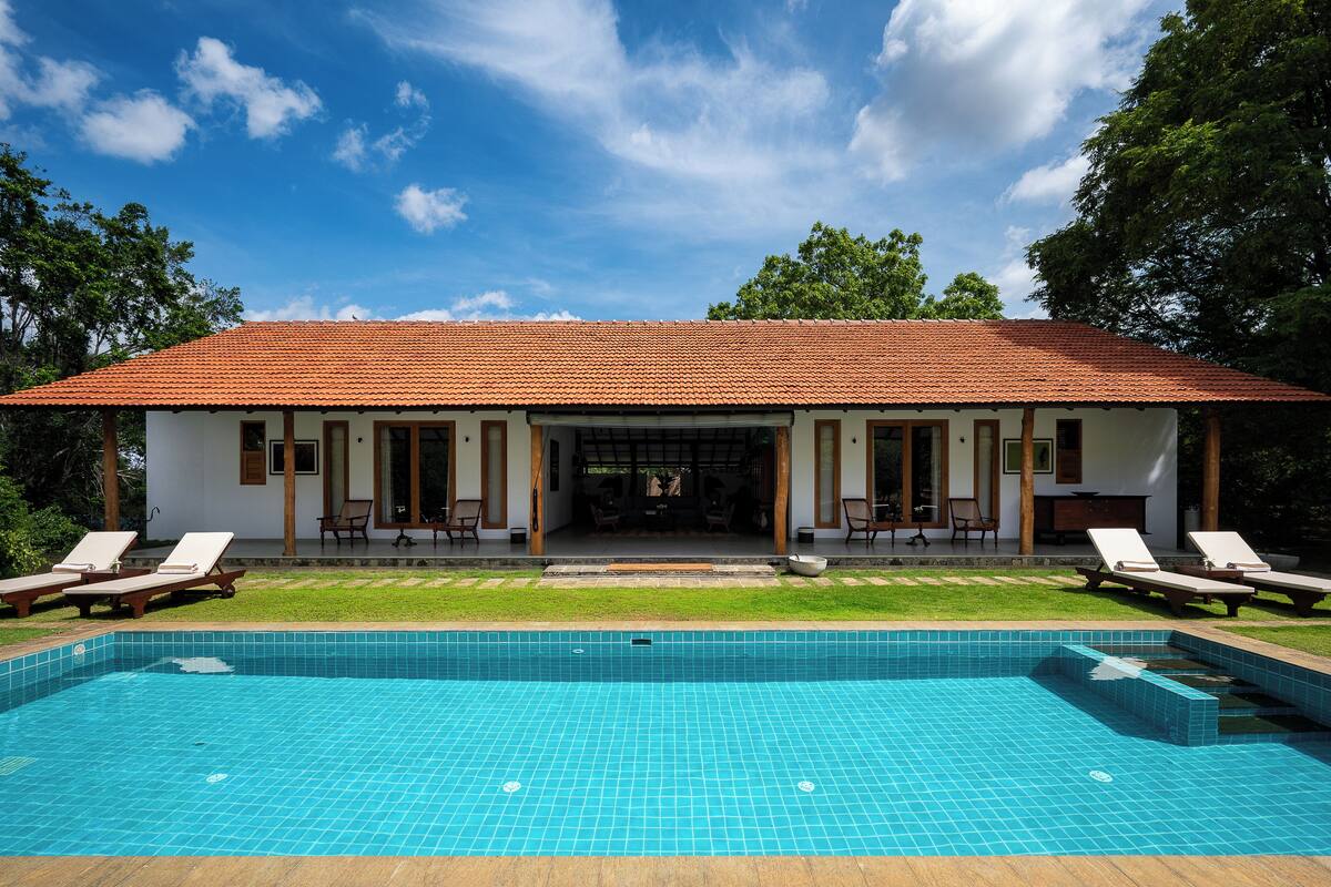 A two-story house with a swimming pool in front.