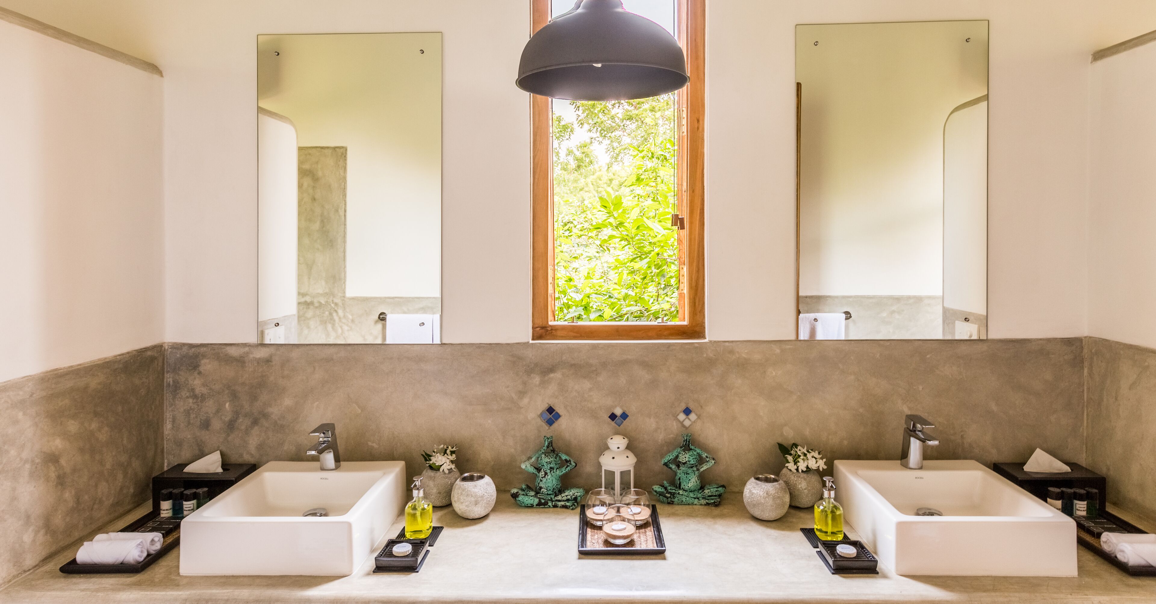 Ein modernes Badezimmer mit zwei Waschbecken, einem großen Spiegel und einem Fenster mit Blick auf Grünflächen.