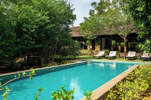A swimming pool surrounded by lush greenery and a building with a tiled roof. - Nyne Hotels Mayur Lodge - Yala (Thissamaharama)