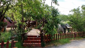 Un puente de madera que conduce a un área cercada con una gran estatua de elefante.