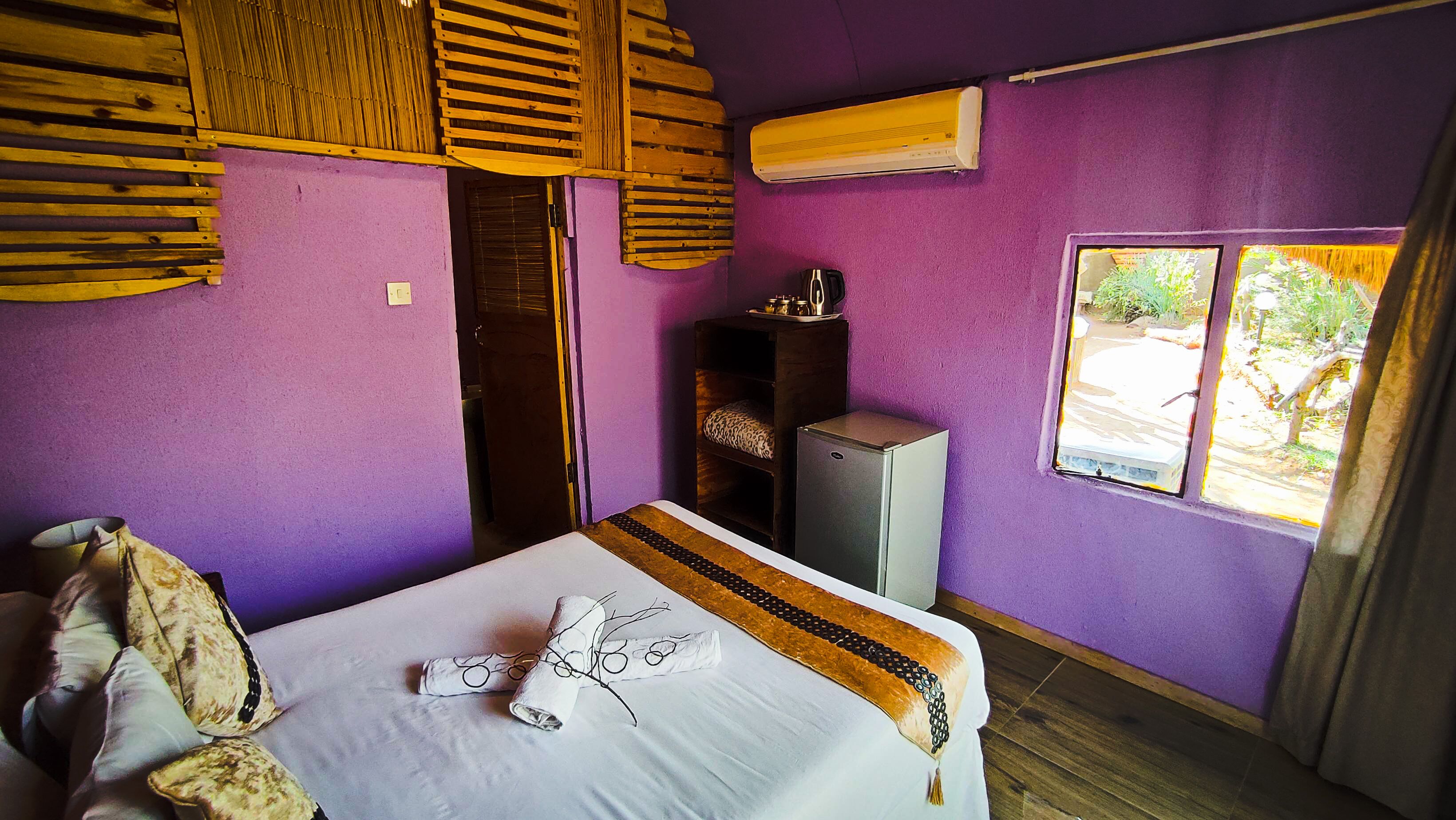 A room with a bed, a wardrobe, a desk, and an air conditioning unit.