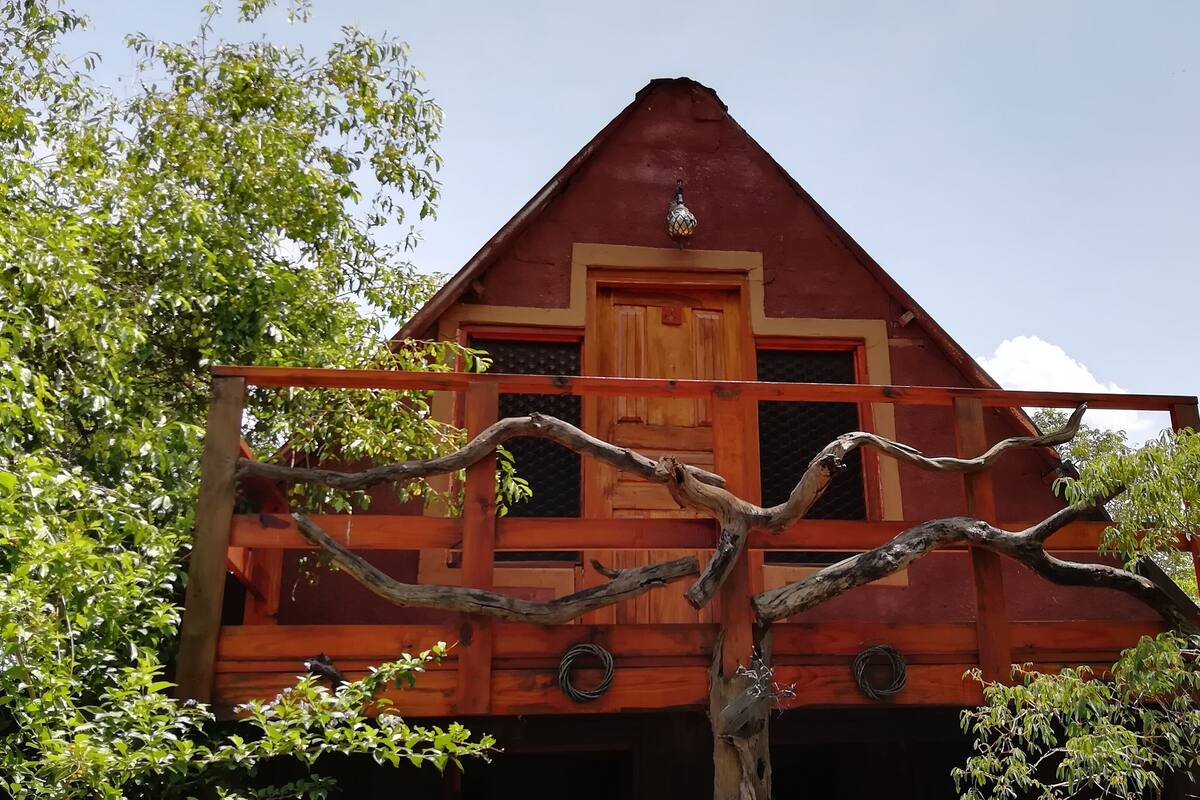 A red wooden building with a triangular roof and a wooden balcony.