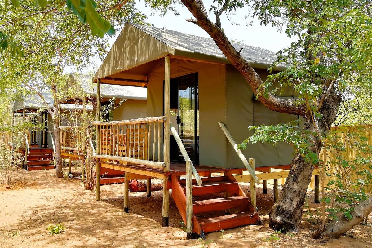 A rustic cabin with a wooden deck and stairs leading to a door.
