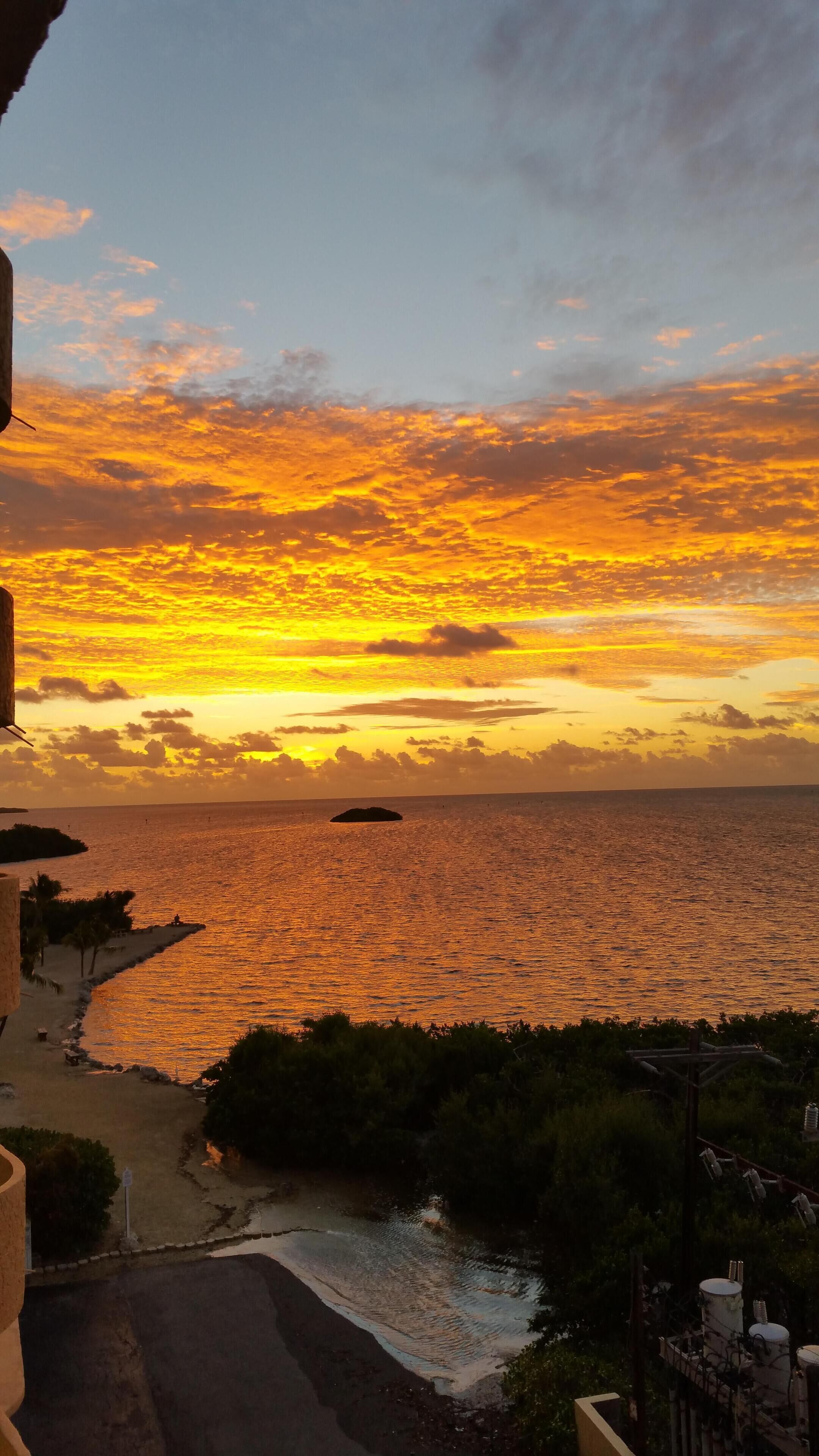 A coastal sunset view with a beach and a small island.