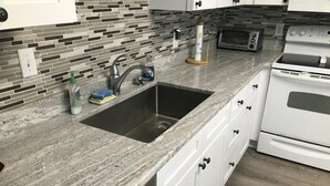 A kitchen with a stainless steel sink, white cabinets, a microwave, and a built-in oven.