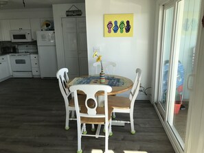 Un coin repas avec une table ronde, des chaises blanches et un vase rempli de fleurs.