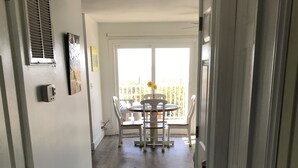 A hallway leading to a balcony with a dining table and chairs.
