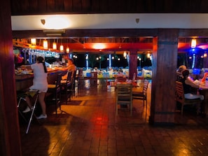 An indoor bar area with tables and chairs, a bar counter, and hanging lights. - OCEAN VIEW COMFORTABLE CONDO BY THE OWNER, 6 POOLS. COCO, COSTA RICA. (Playas Del Coco)