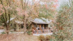 A rustic cabin with a porch, surrounded by trees and a garden. - We weathered Helene beautifully!      Welcome to your new, lovely mountain home! (Asheville)