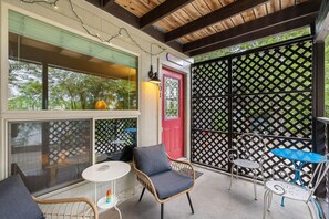 A covered outdoor seating area with wicker chairs and a table, a red door, and a lattice fence. - Private, 1 King bed, Patio; .33 mi to Zilker Park/Barton Springs, @2 mi to DT! (Austin)