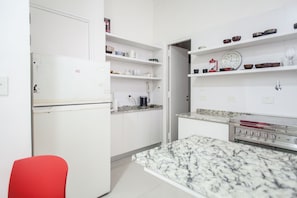 Compact kitchen with stove, microwave, and ample shelving for kitchen essentials.