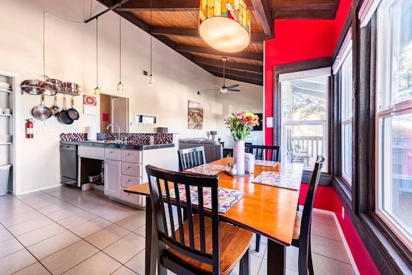 A modern kitchen with a dining area, featuring a wooden table, chairs, and a red accent wall.