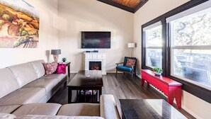 A living room with a fireplace, a television, and a large window. - Accessible Duplex Walking Distance to Park, Springs & Trails (Austin)