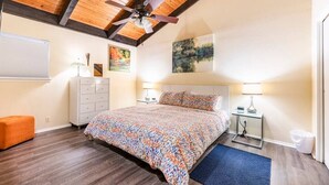 A bedroom with a wooden ceiling, a bed with a patterned bedspread, two bedside tables with lamps, and a window with blinds. - Accessible Duplex Walking Distance to Park, Springs & Trails (Austin)