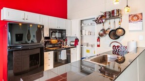 A modern kitchen with white cabinets, a black refrigerator, stainless steel appliances, and hanging pots. - Accessible Duplex Walking Distance to Park, Springs & Trails (Austin)